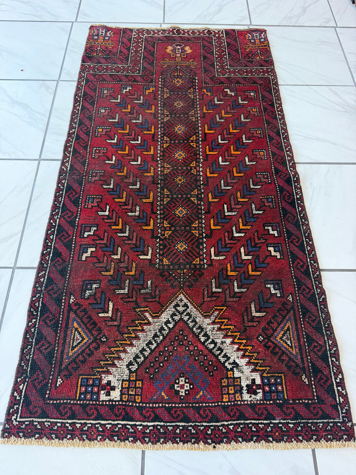 Vintage Baluch prayer rug 3x6 | lying flat, viewed from one end | red tribal wool