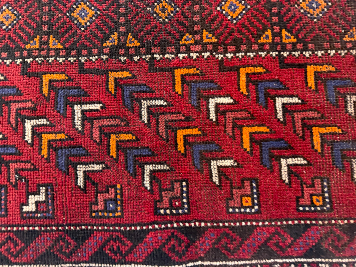Baluch rug close-up | diagonal chevron rows | navy ivory orange on red